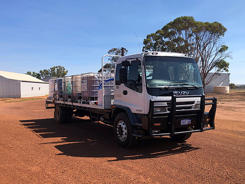 Truck parked near shed with containers on the back.